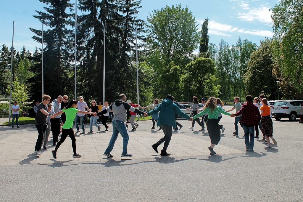 Opiskelijat ja henkilökunta tanssivat ringissä opiston pihalla