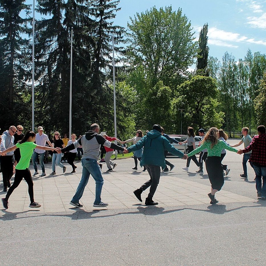 Opiskelijat ja henkilökunta tanssivat ringissä opiston pihalla